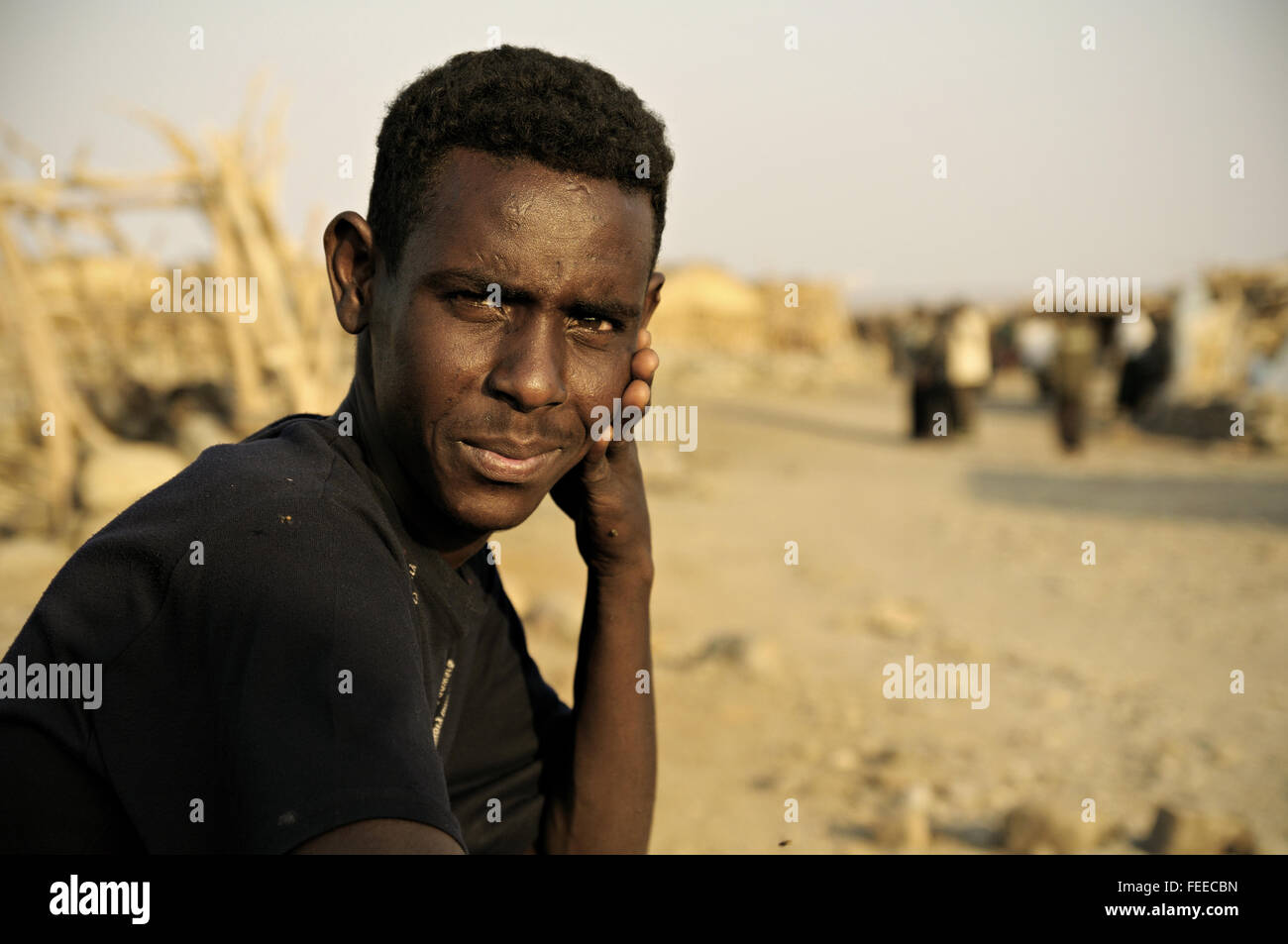 Young african man sitting in the village of Ahmed Ela, Danakil depression, Afar Region, Ethiopia Stock Photo