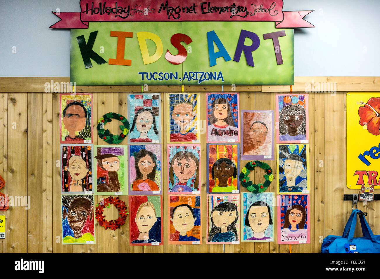 children's watercolor self portraits labeled Kids Art & displayed on knotty pine wainscot of wall next to entrance Trader Joes Stock Photo