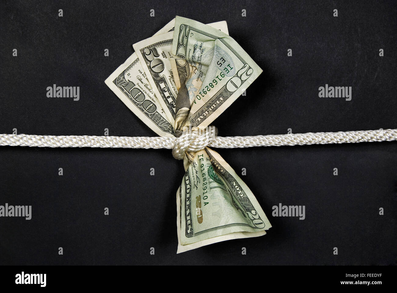 American money knotted tight in a rope isolated on black. Stock Photo