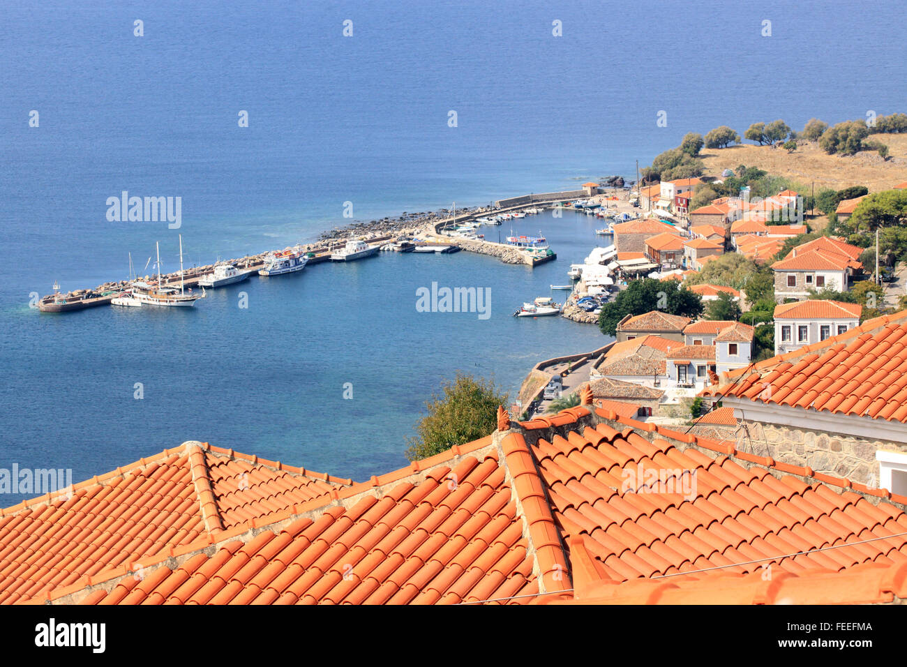 View over the red clay tiled rooftops towards the small fishing harbour at the Aegean sea resort of Molyvos on the Greek Island of Lesbos Greece Stock Photo
