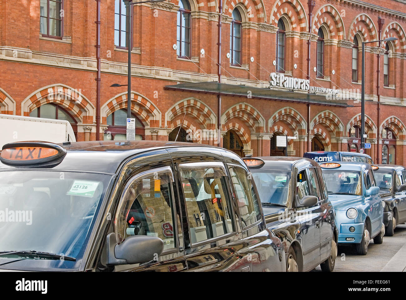 A line of iconic black London taxi cabs wait outside St Pancras International station, arrival point for Eurostar and national rail services. Stock Photo