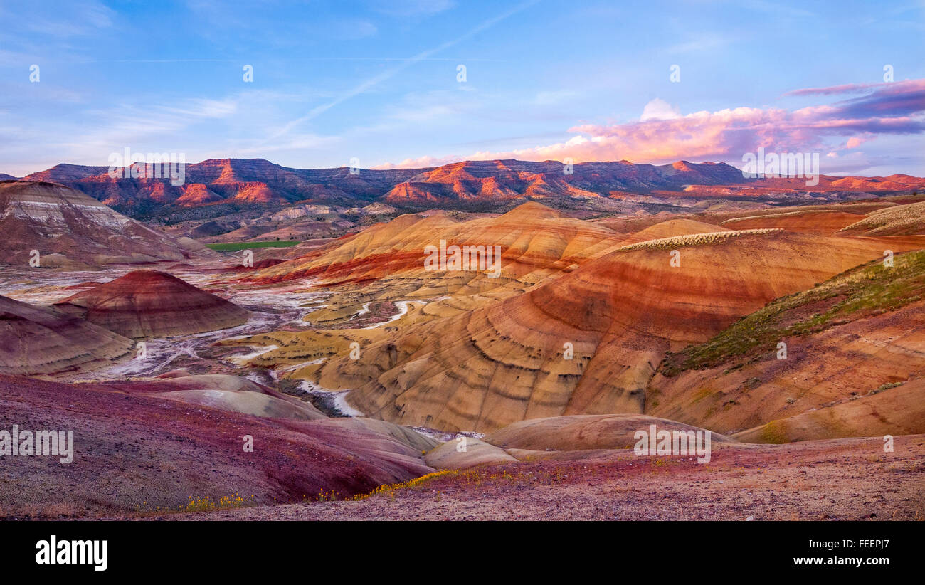 The last rays of the setting sun light the bluffs far behind the Painted Hills. Oregon, USA. Stock Photo