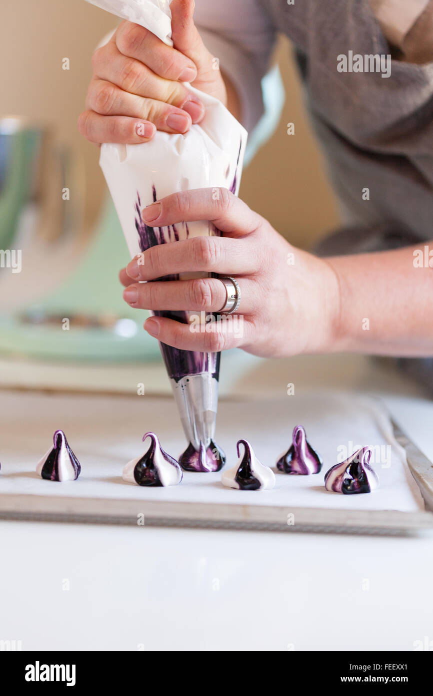 close up of a Caucasian woman piping meringue in her kitchen Stock Photo