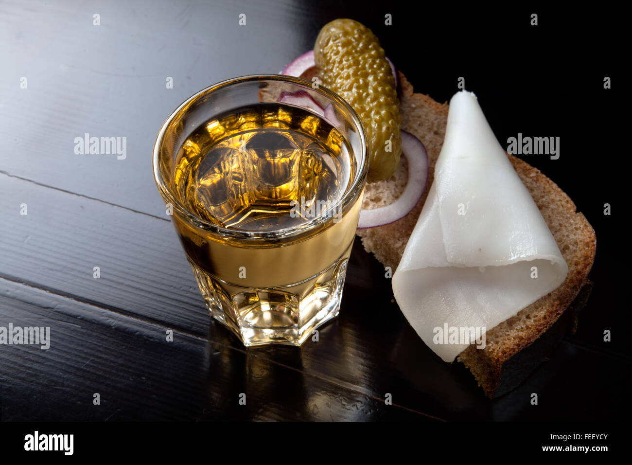 Russian vodka in small glass with black bread, pickled, onion and bit of lard on black background Stock Photo
