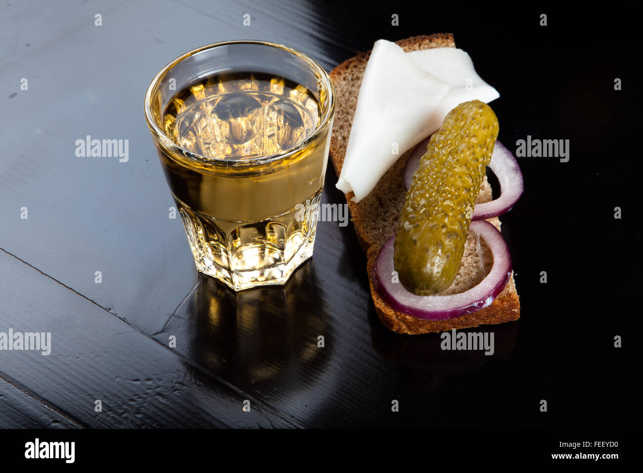 Russian vodka in small glass with black bread, pickled, onion and bit of lard on black background Stock Photo