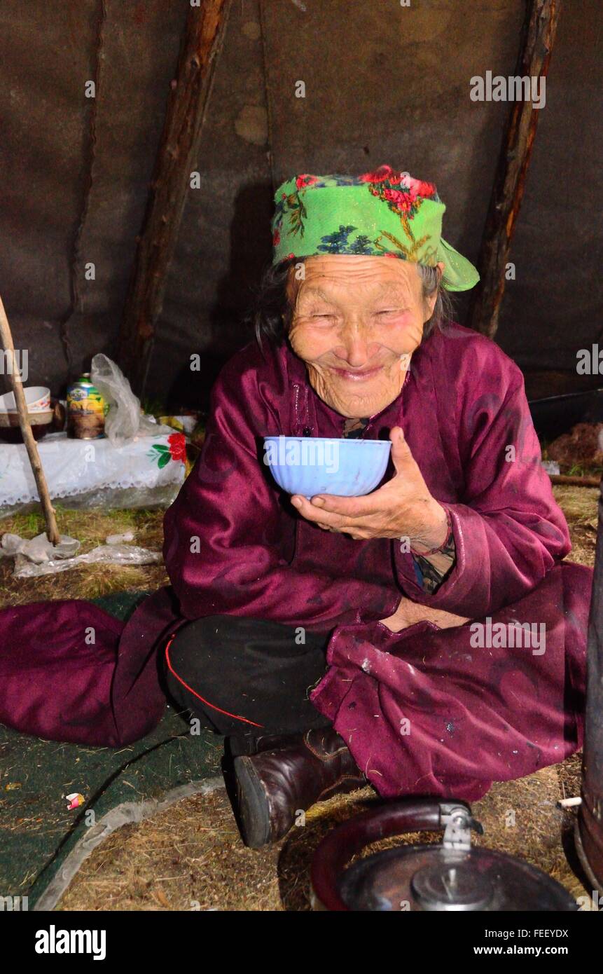 Old Duhkha (same as Tsaatan) woman drinking tea inside her tent Stock Photo