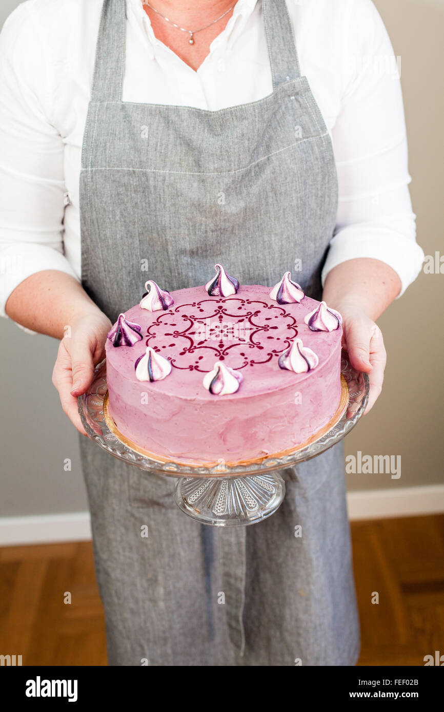 woman holding a decorated lilac cake with meringues Stock Photo
