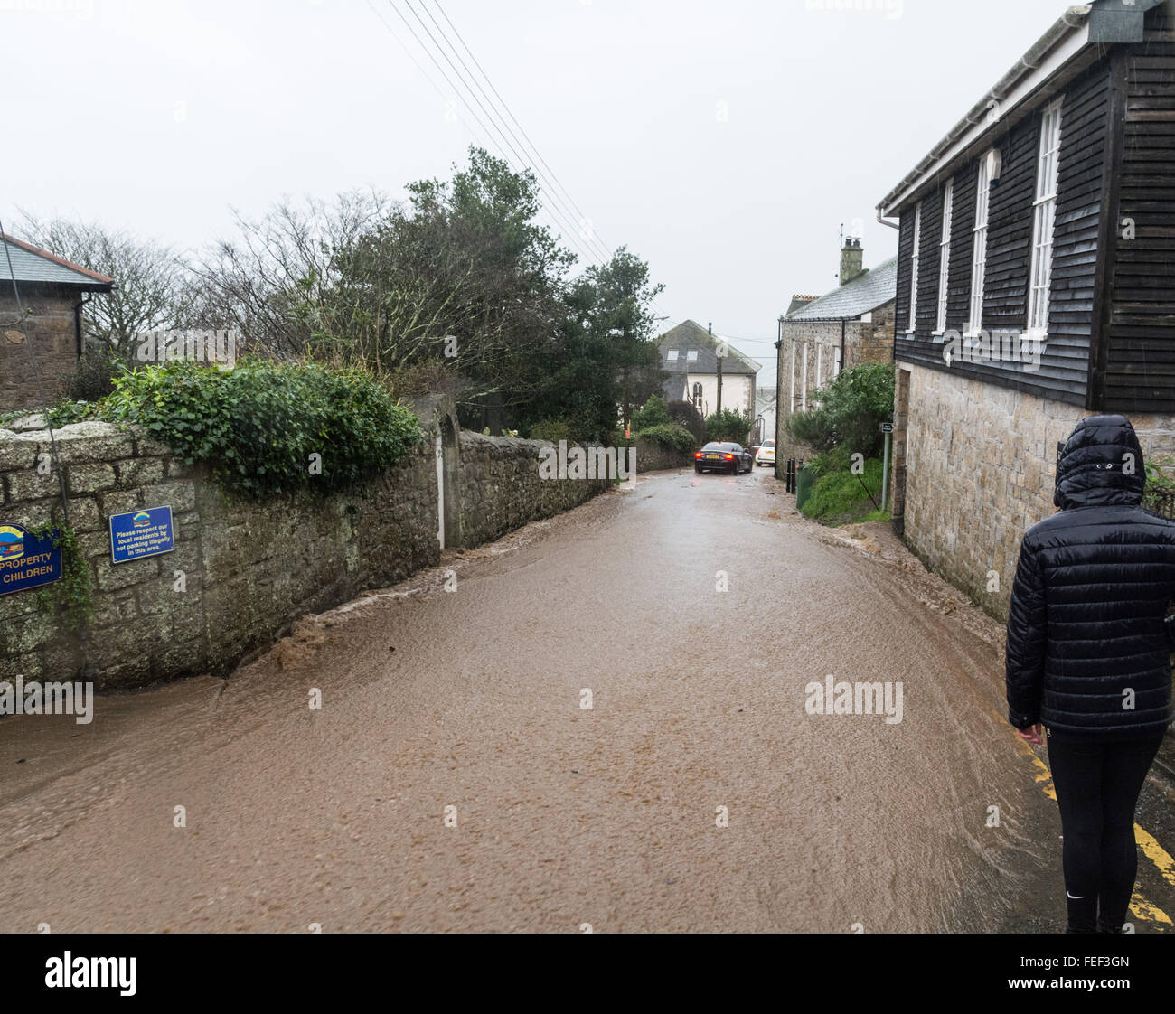 Mousehole, Cornwall, UK. 6th February 2016. UK Weather. Residents of the village of Mousehole in Cornwall awoke to heavy rain and a torrent of water, which is threatening to flood properties and damage parked cars. Credit:  Simon Maycock/Alamy Live News Stock Photo