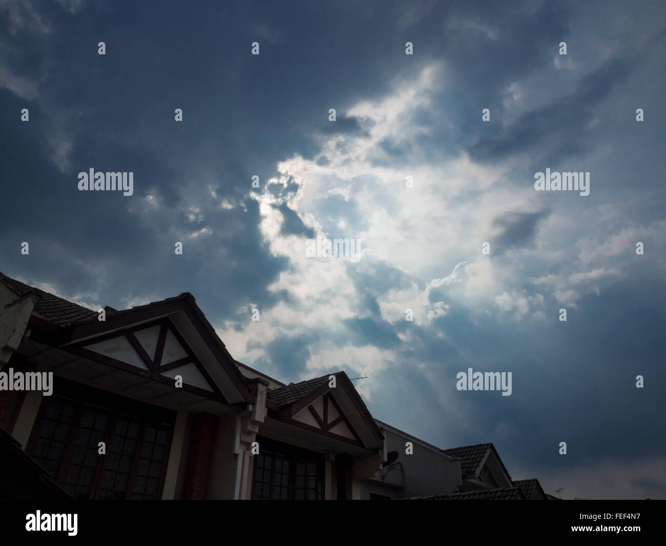 Light bleeding through clouds over houses Stock Photo Alamy