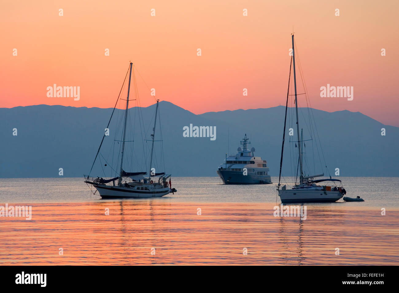 Corfu Town, Corfu, Ionian Islands, Greece. View across the tranquil waters of Garitsa Bay, dawn, yachts at anchor. Stock Photo
