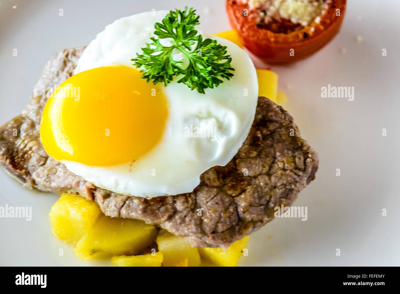Sirloin steak topped with fried egg and breakfast potatoes Stock Photo