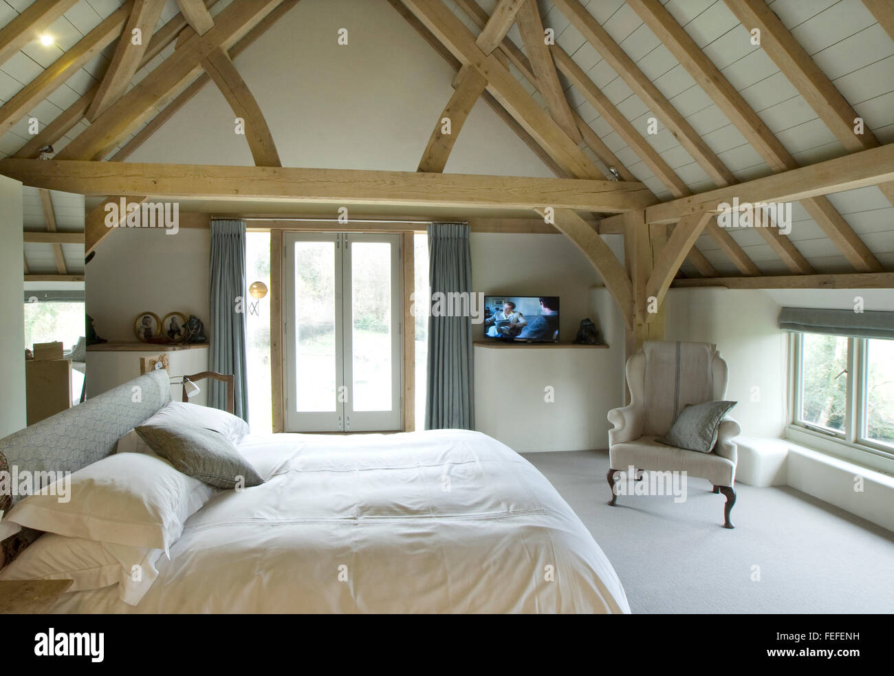 Master bedroom in barn conversion. Oak ceiling, french windows. New build Stock Photo