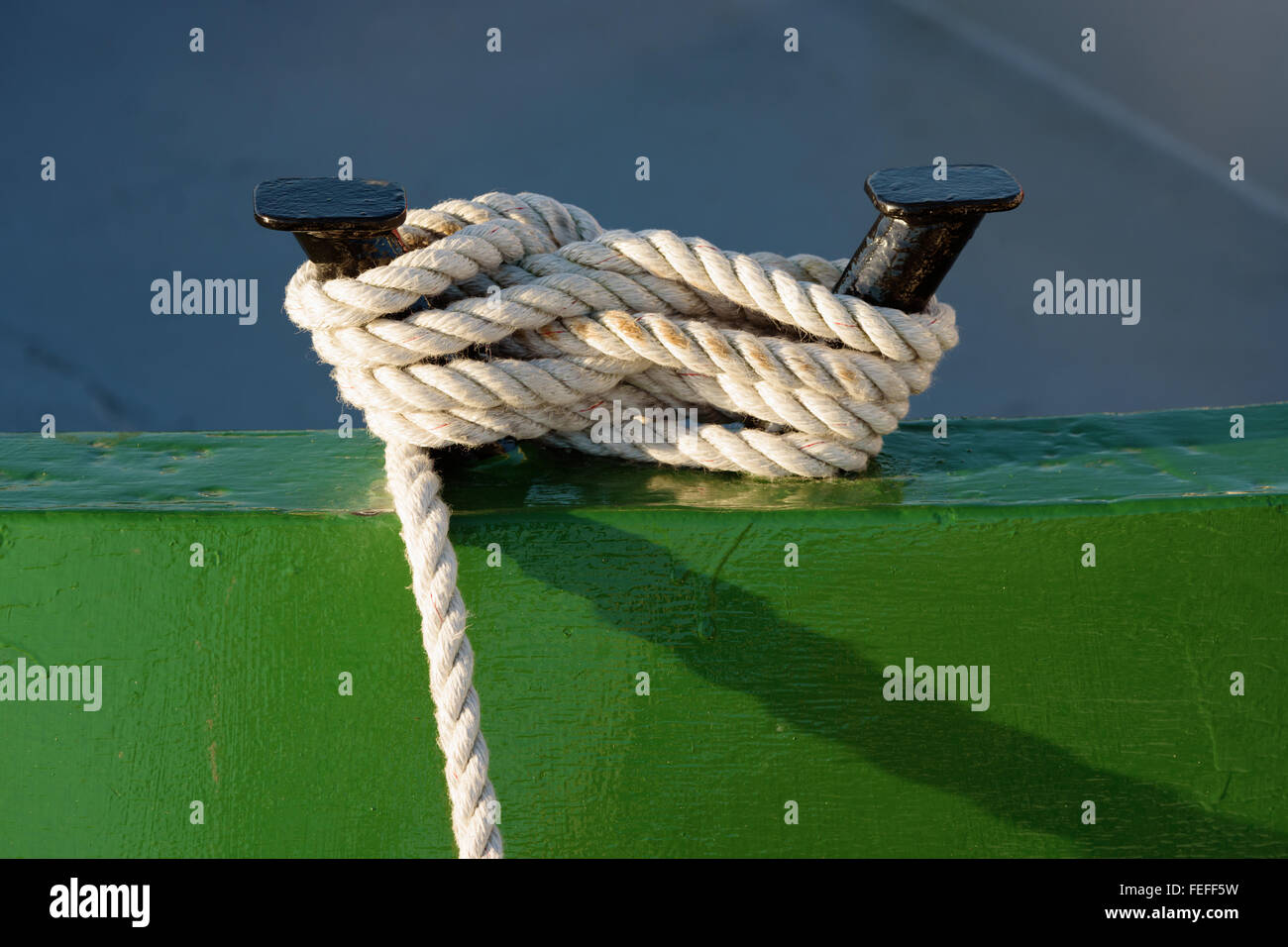 Detail of a white rope tied to a black metal anchor point on a