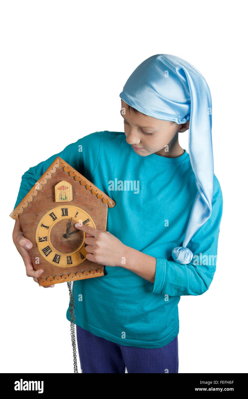 Cute boy in blue pajamas and sleeping hat holding clock isolated on
