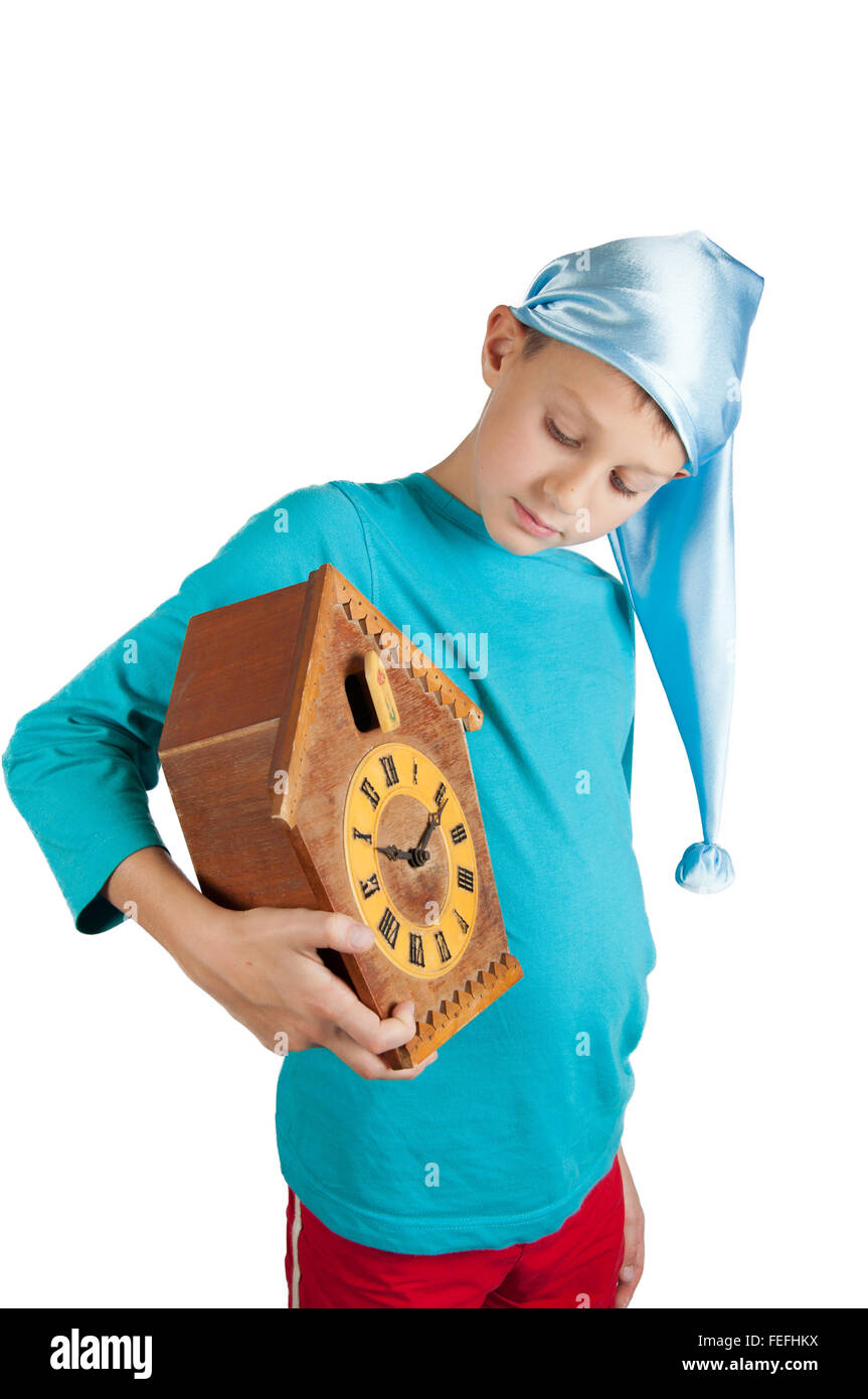 Cute boy in blue pajamas and sleeping hat holding clock isolated on