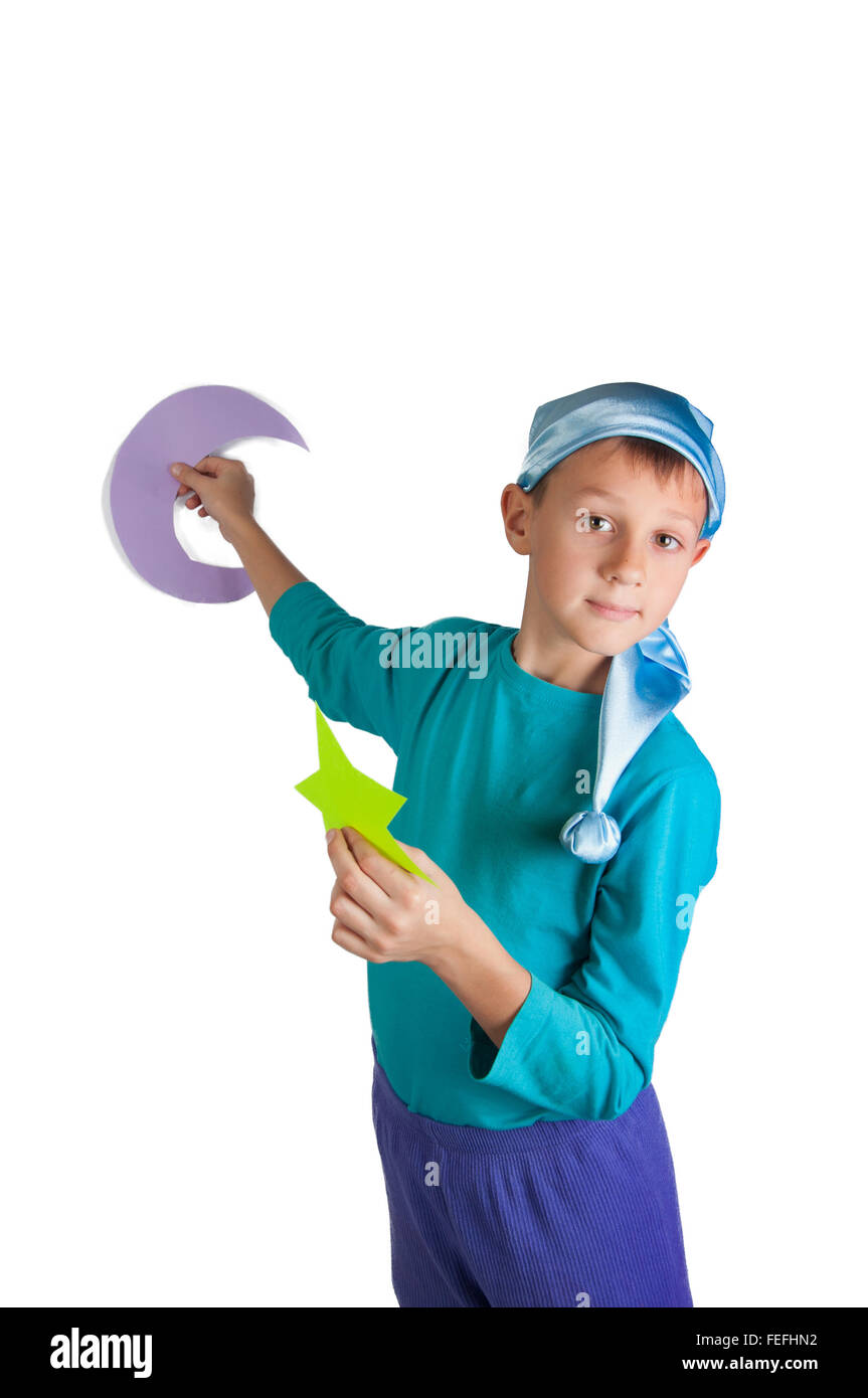 Cute boy in blue pajamas and sleeping hat holding paper moon and stars