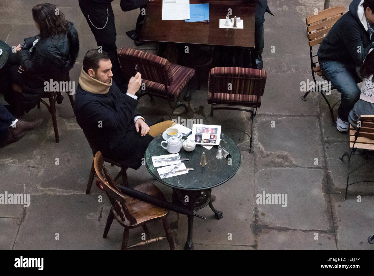 A young man texting on his telephone while having tea in a café, London, United Kingdom. Stock Photo