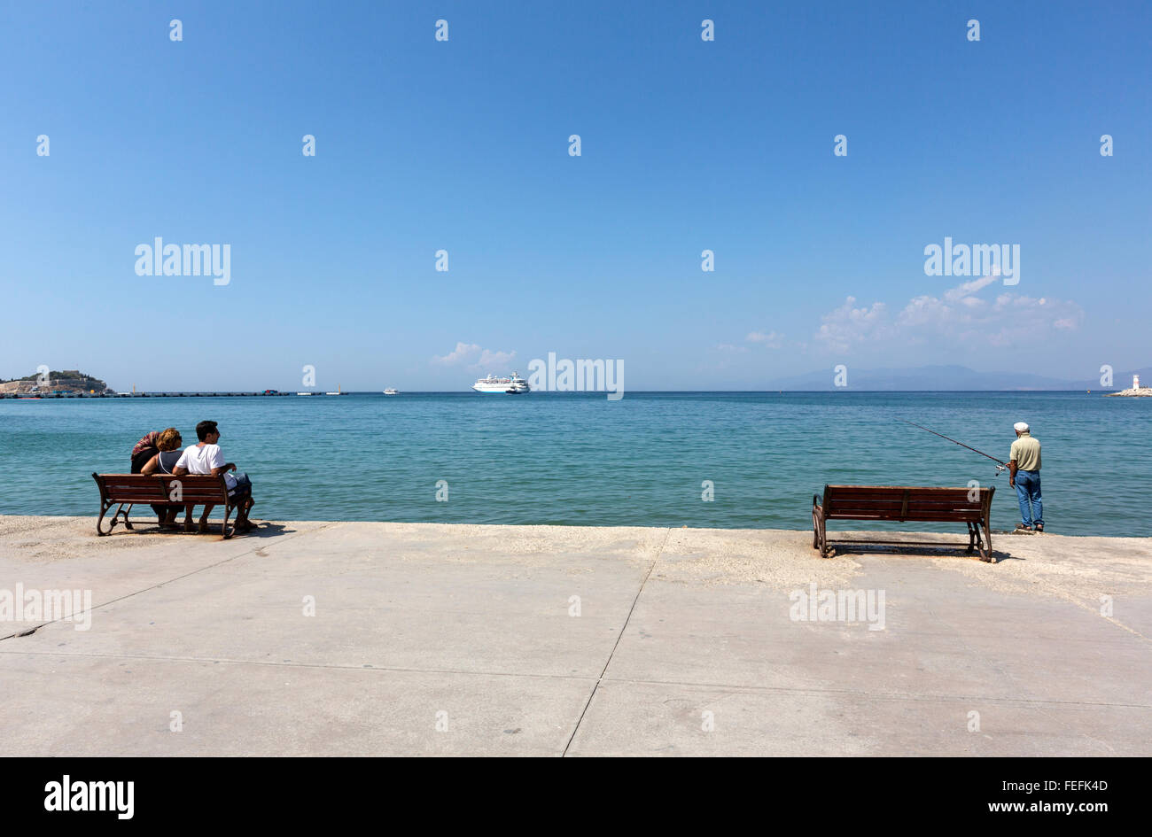 Family looking a man fishing in the Aegean sea in the Promenade in Atatürk Boulevard looking the in Kuşadası,  Turkey Stock Photo