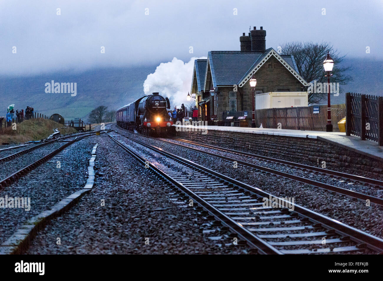 Ribblehead, North Yorkshire, UK. 6th February, 2016. The famous Flying Scotsman steam locomotive runs over the Settle-Carlisle Railway Line past Ribblehead Station, North Yorkshire, late on 6th February 2016. This is the loco's first outing on the Settle-Carlisle since its recent restoration. Stock Photo
