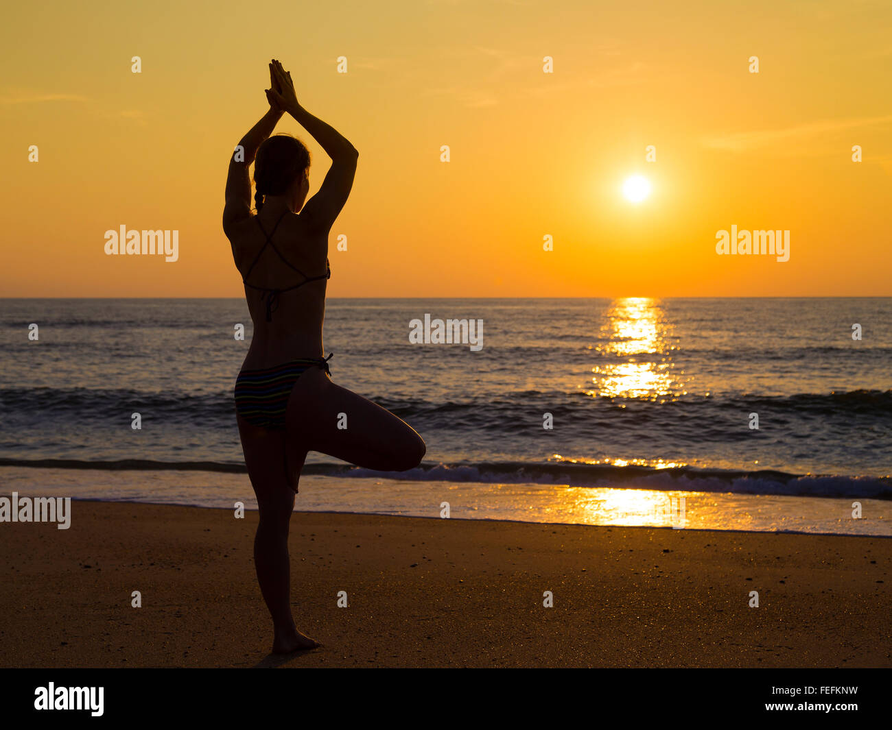 Young woman practicing yoga on the beach at sunset Stock Photo - Alamy
