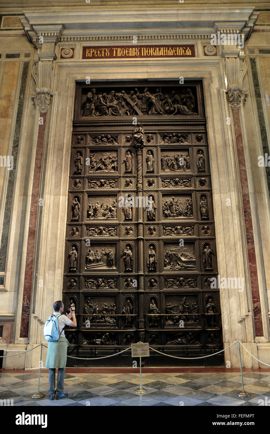 A tourist photographs the bronze doors, covered in reliefs by Ivan Vitali, inside St Isaac's Cathedral, St Petersburg, Russia. Stock Photo