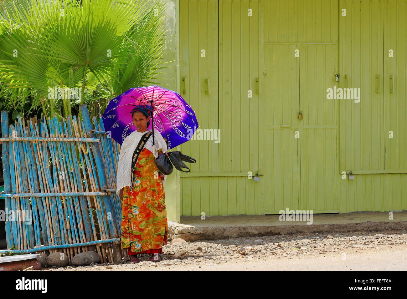 DEBRE BIRHAN-ETHIOPIA-MARCH 24: Local young woman with umbrella waits for the bus to come while standing on the main street. Stock Photo