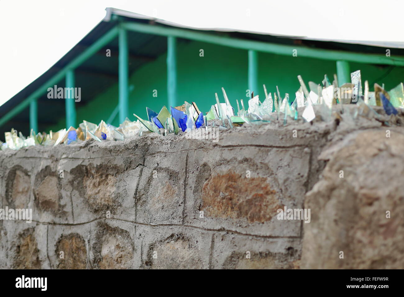 Stone and concrete wall topped with broken glasses for security of a