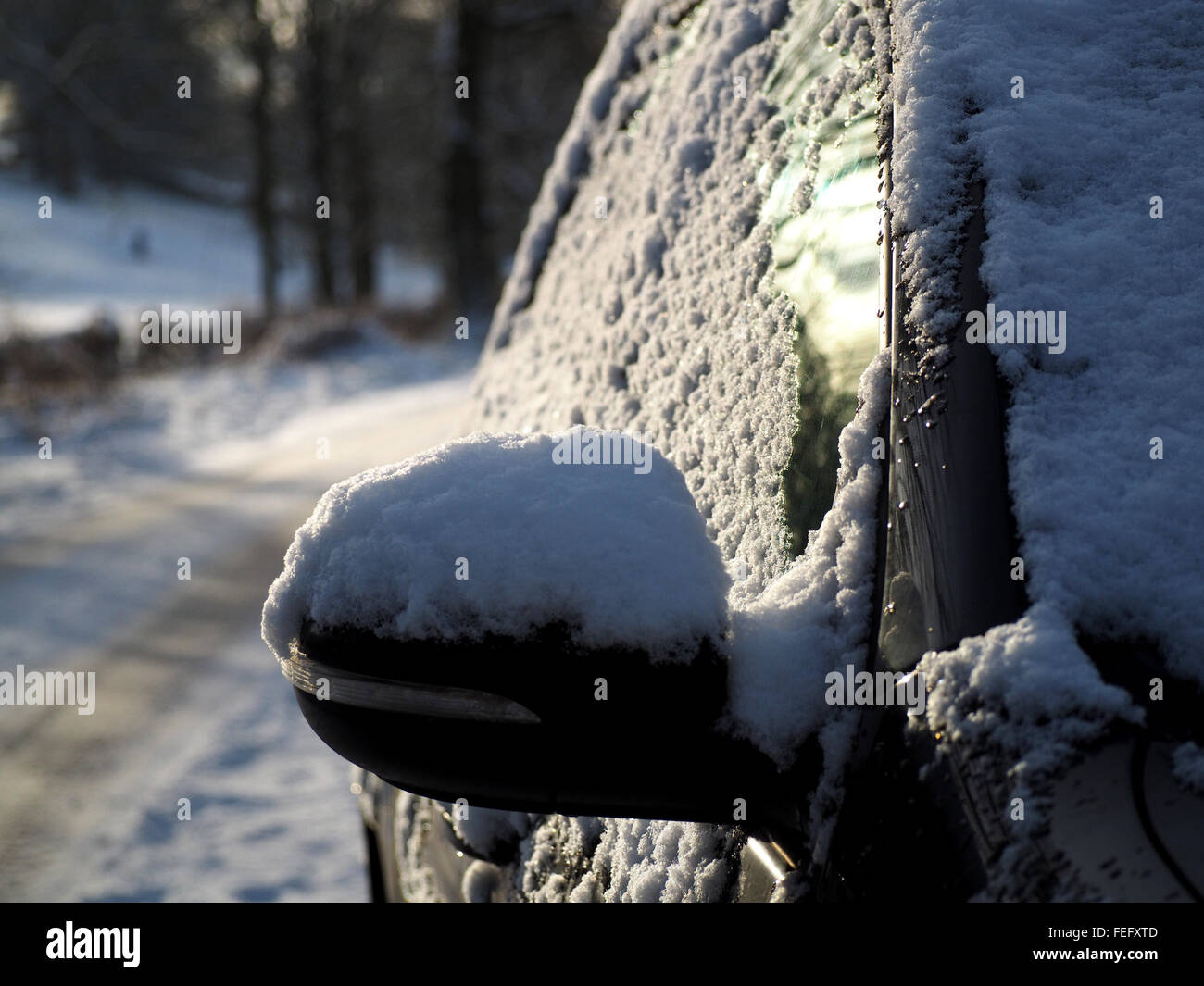Car wing mirror and windows with a covering of snow in winter on a slippery northern rural road Stock Photo