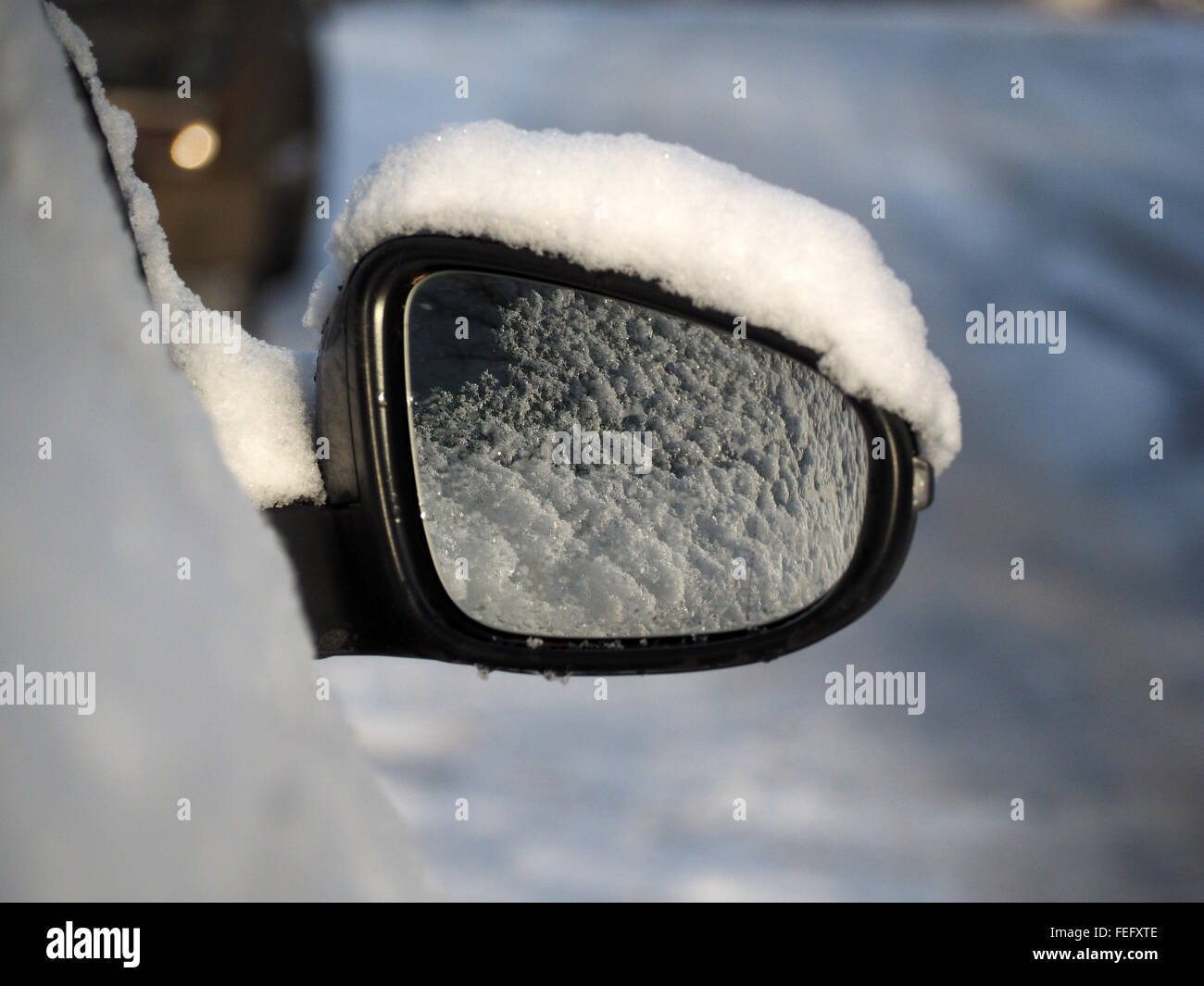 Car wing mirror with a covering of snow in winter on a slippery northern rural road Stock Photo