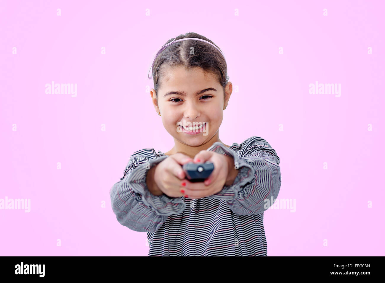 Little girl holding remote control isolated on pink background Stock Photo