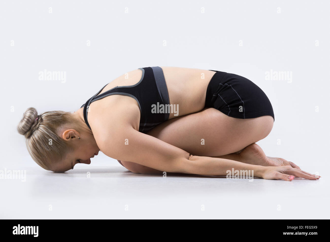 Sporty beautiful young woman practicing yoga, doing Balasana, Child Pose, restorative exercise for stress relief, working out Stock Photo