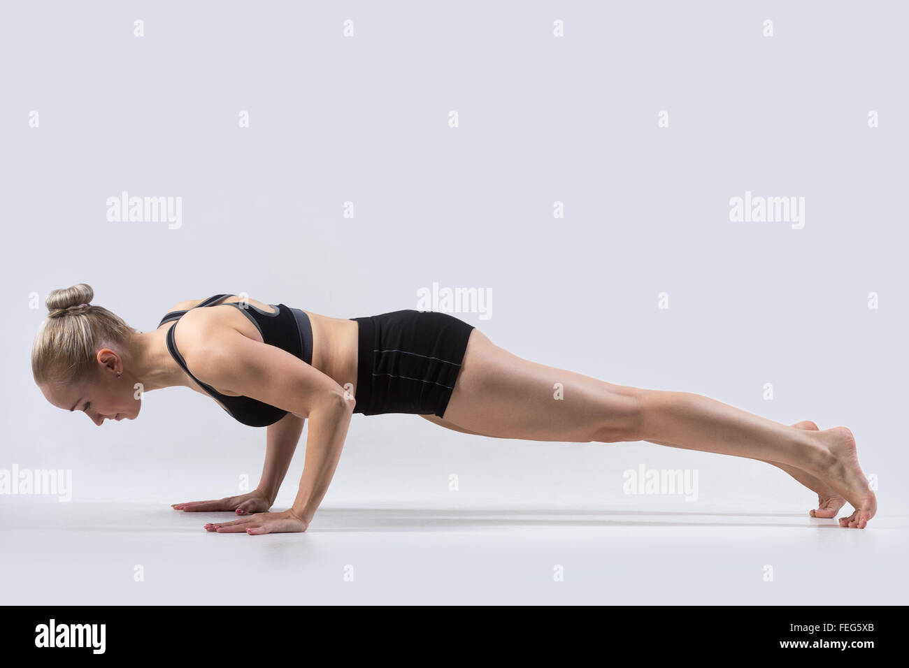 Sporty beautiful young woman practicing yoga, doing chaturanga dandasana (four-limbed staff pose) for abdominal muscles Stock Photo