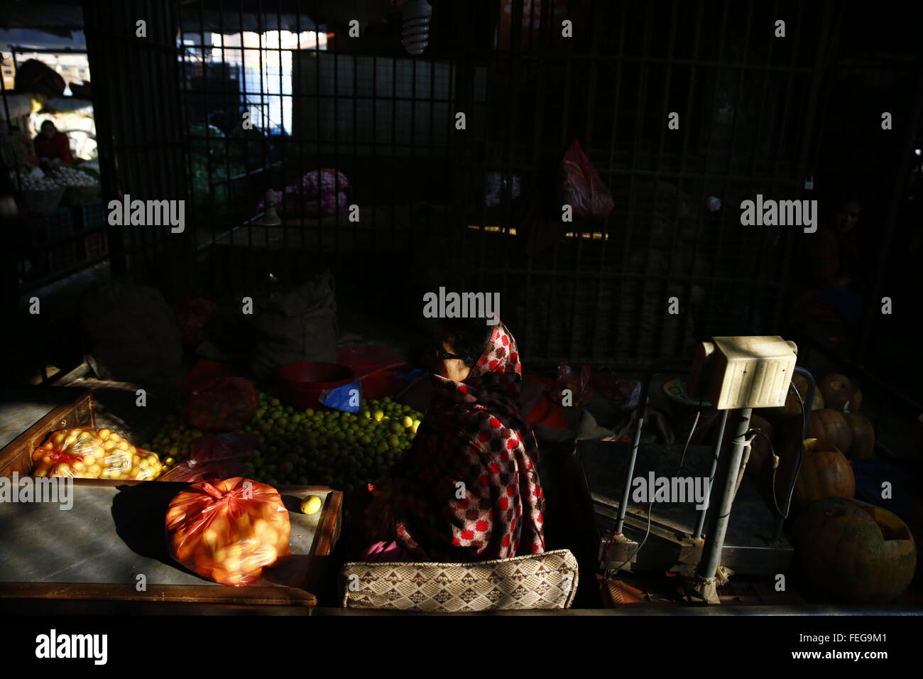Kathmandu, Nepal. 7th Feb, 2016. Light illuminates a woman as she awaits purchasers at Fruits