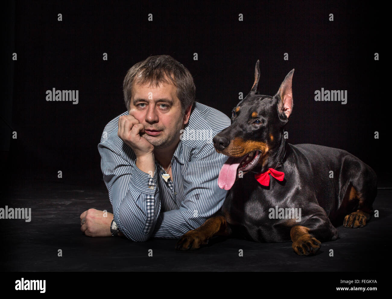 Caucasian man with black doberman dog on black background Stock Photo