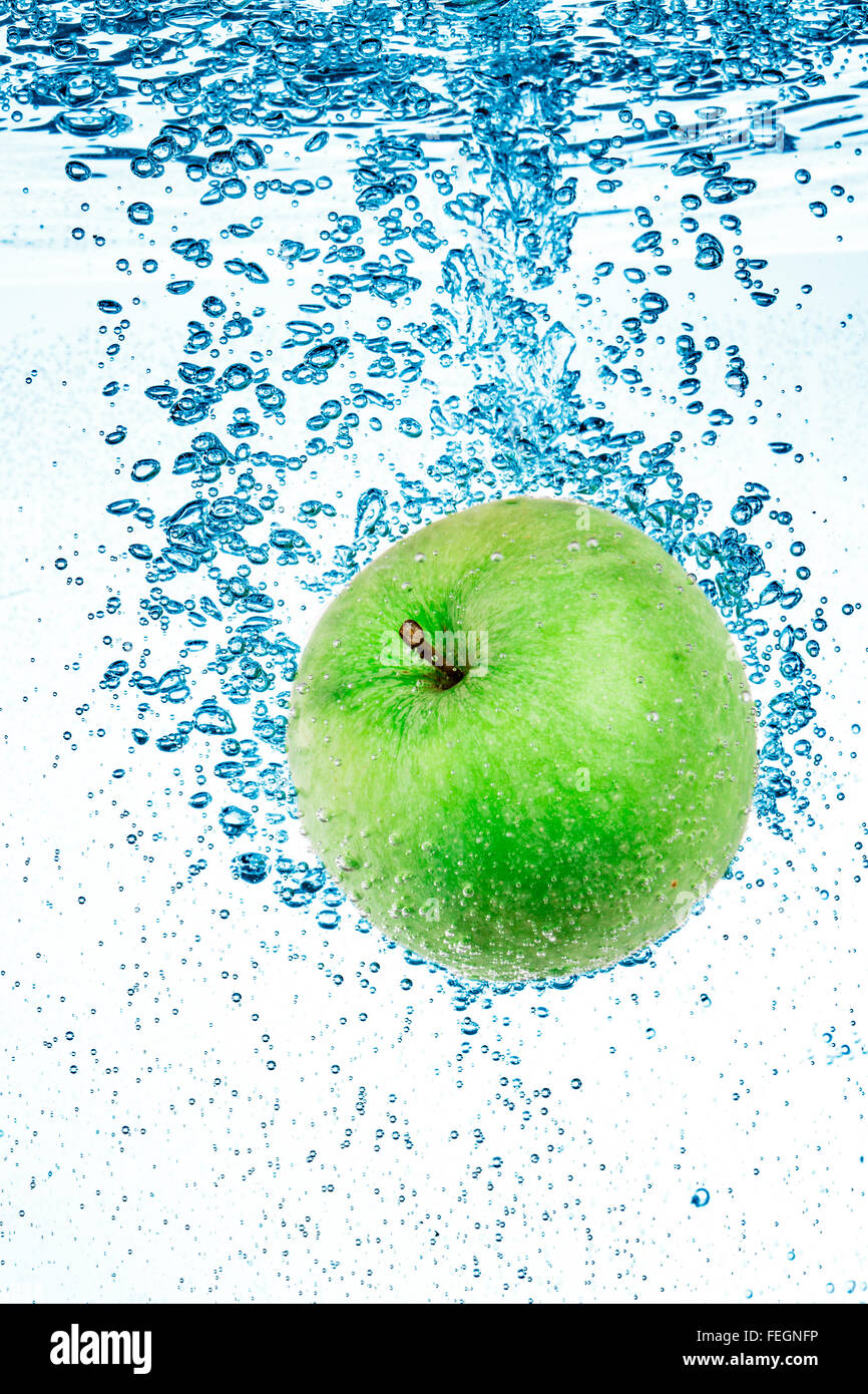 Fresh green apple in the clear water on white background. Stock Photo