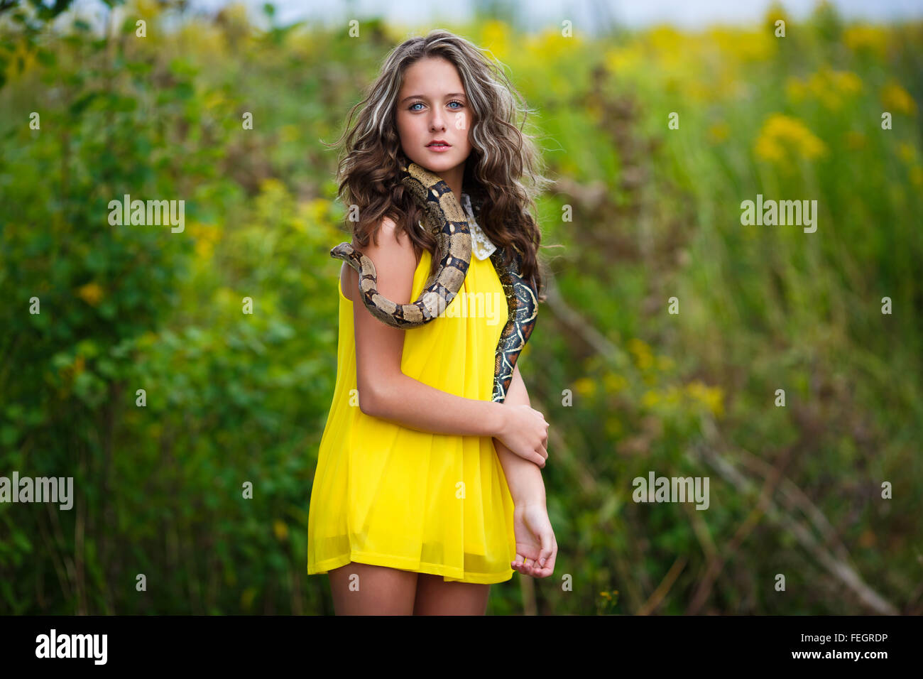 Beautiful young girl with snake in a park Stock Photo