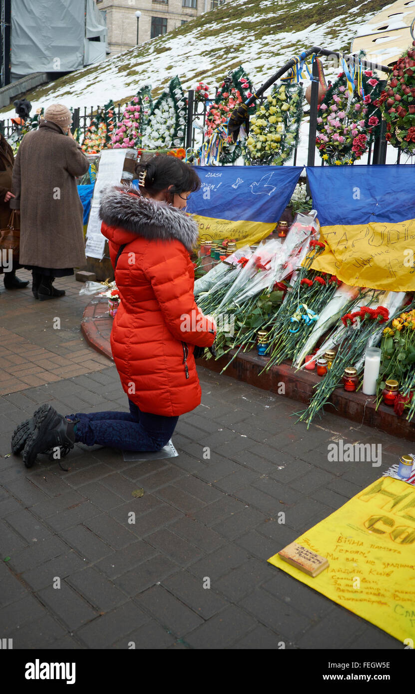 Kyiv, UKRAINE - February 20, 2015: Woman praying on the knees at the Wall of Remembrance of killed anti-government protesters Stock Photo