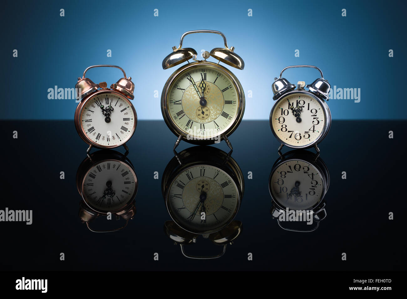 Vintage alarm clocks showing five minutes to twelve, blue background