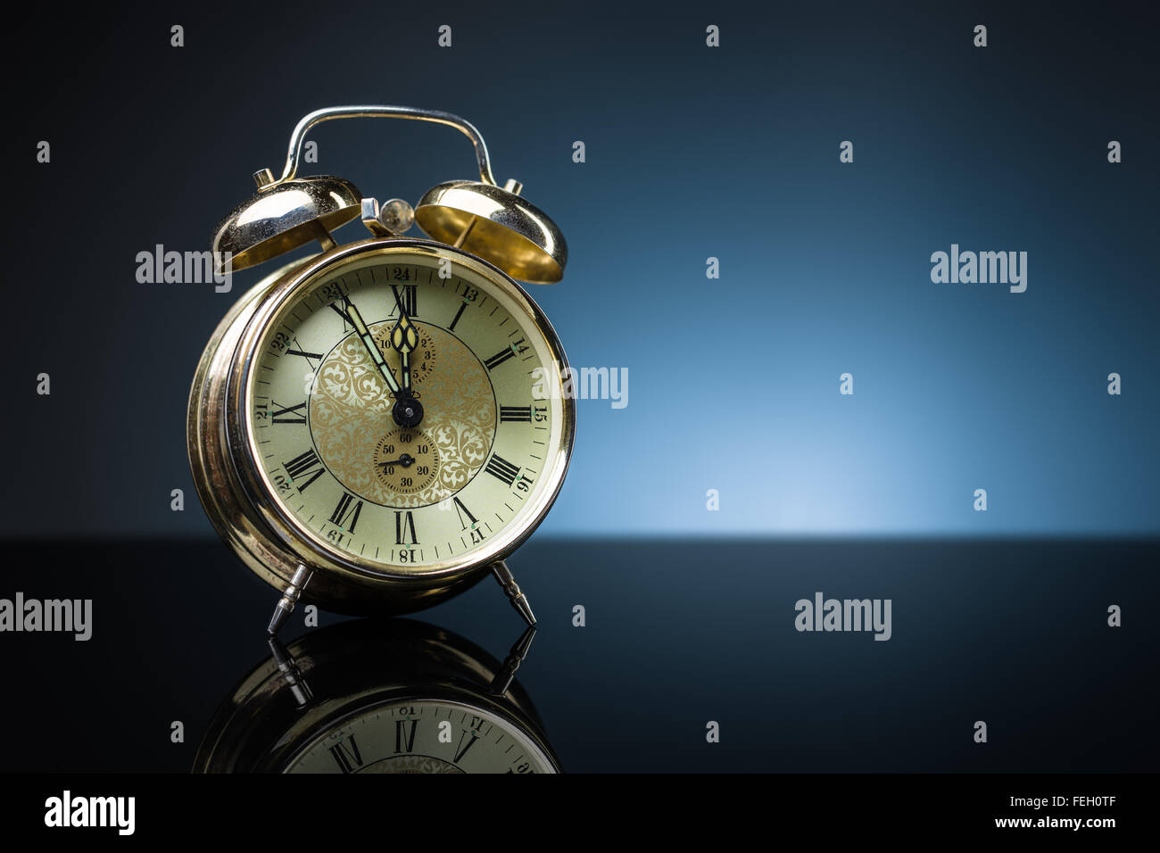 Vintage alarm clock showing five minutes to twelve, blue background, copy space Stock Photo