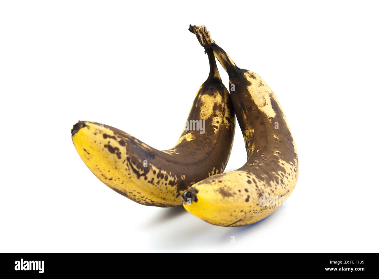 Two overripe bananas with large brown spots on a white background Stock Photo