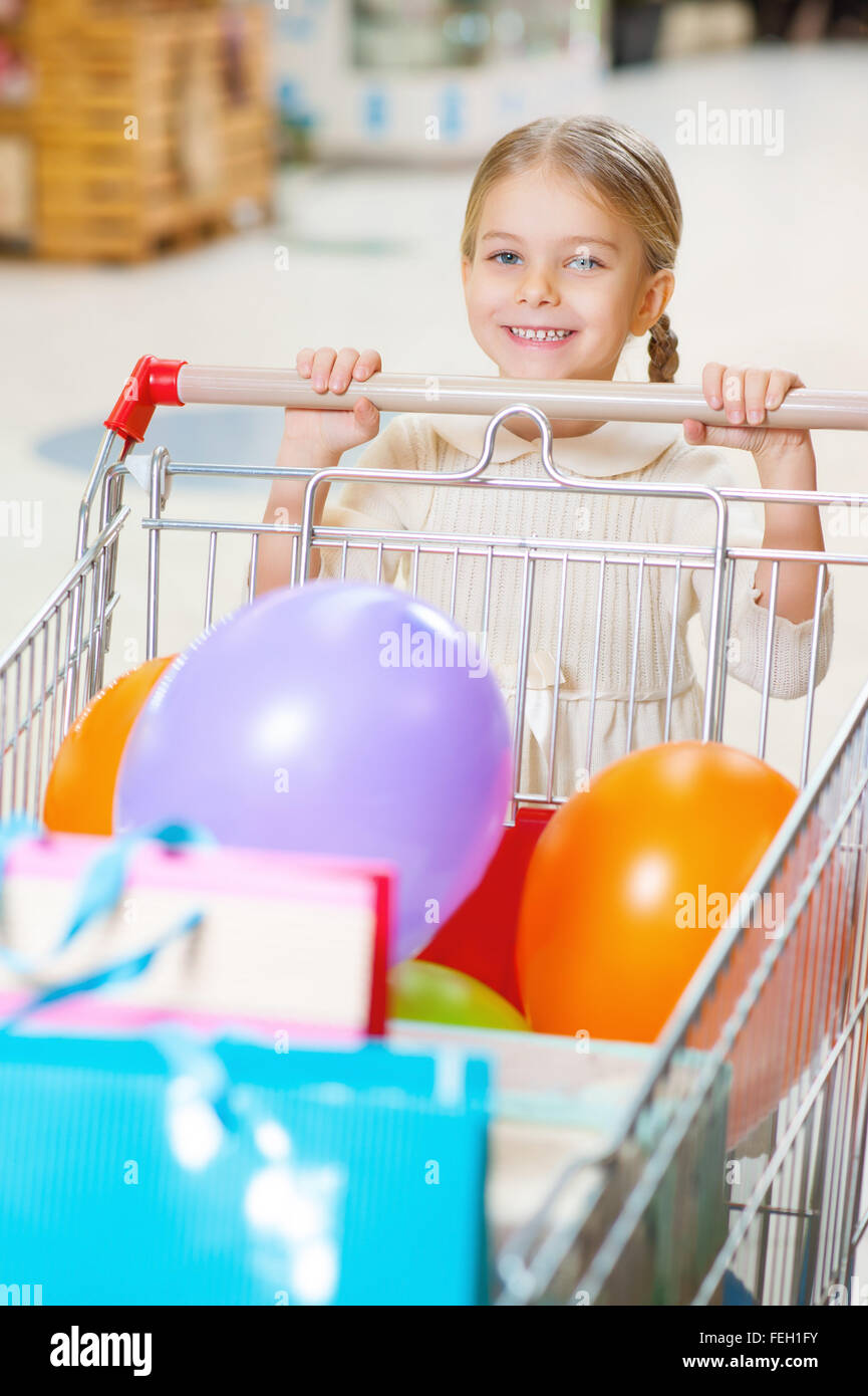 Little smiling girl with trolley at the shop. Stock Photo