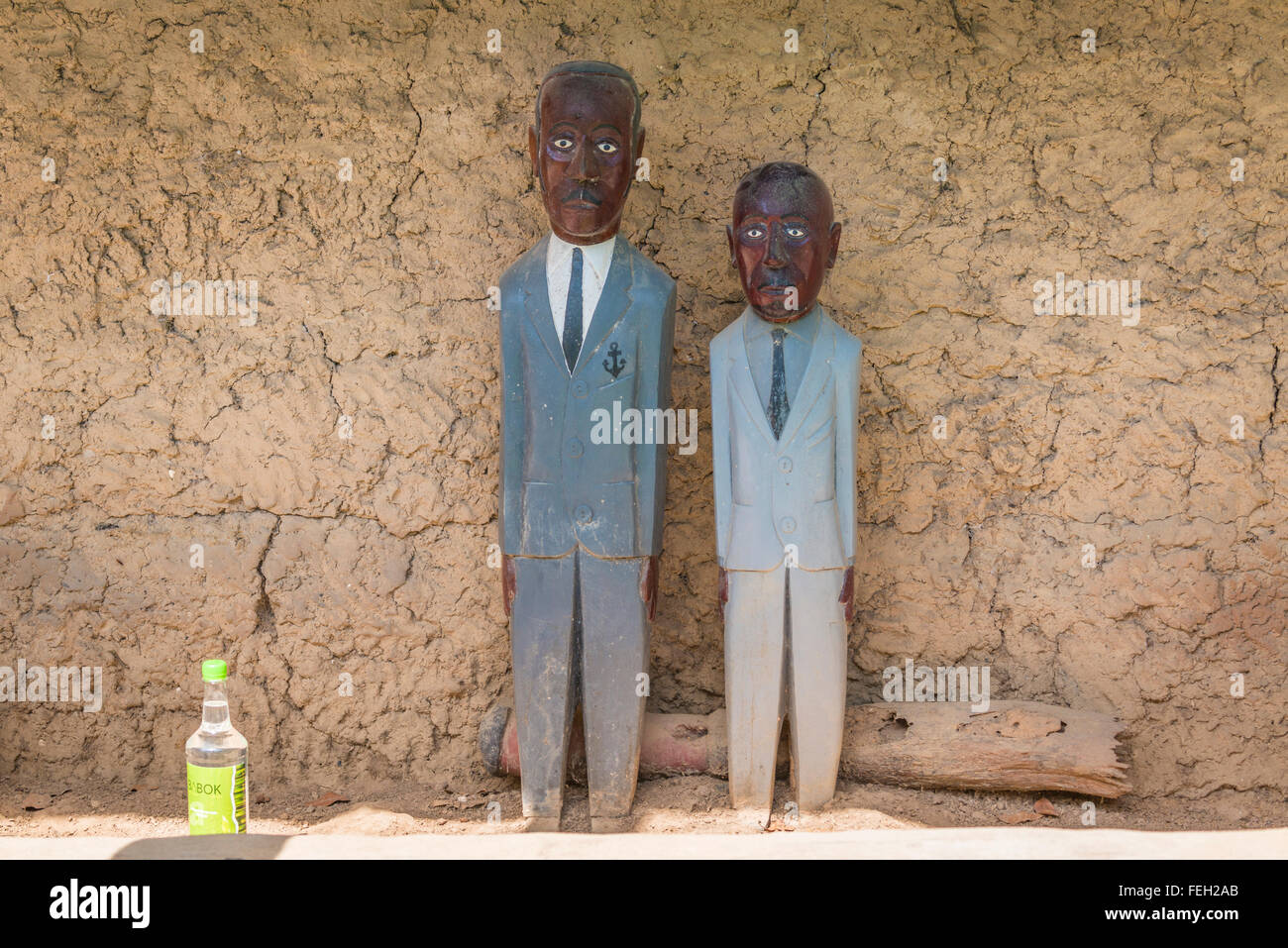The effigies of deceased relatives at a shrine near their home in a northern Guinea Bissau village with an offering of local can Stock Photo