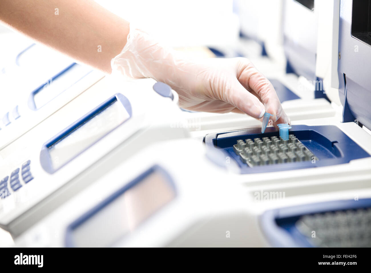 Scientist, DNA copying, Real-time PCR cycler, white gloves, distant Stock Photo