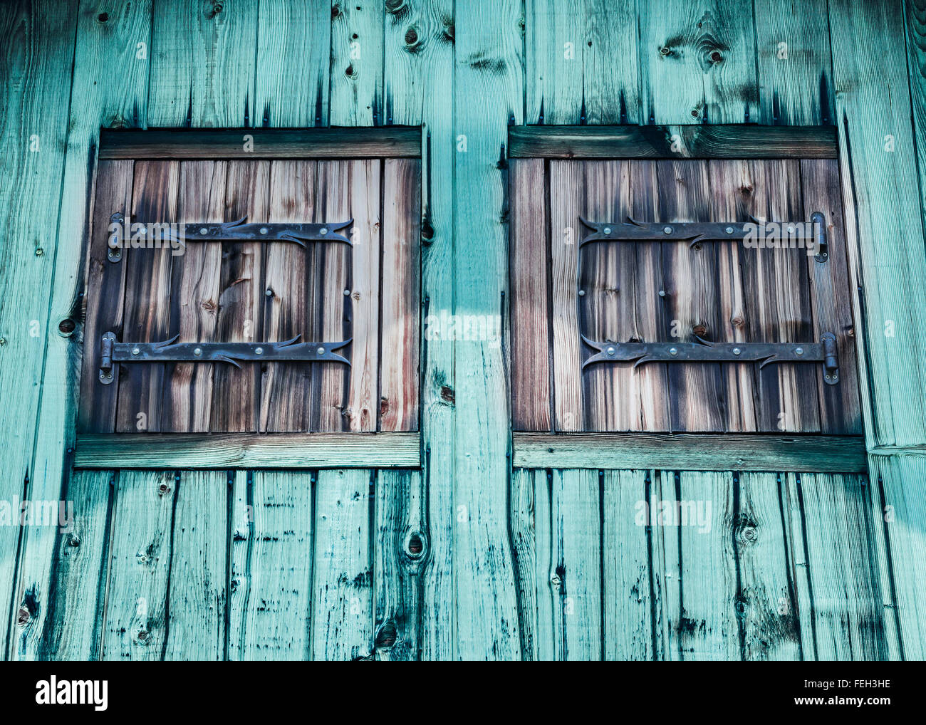 Rustic facade of a wooden house with wooden shutters. Typical facade  -  houses in  the mountains. Stock Photo