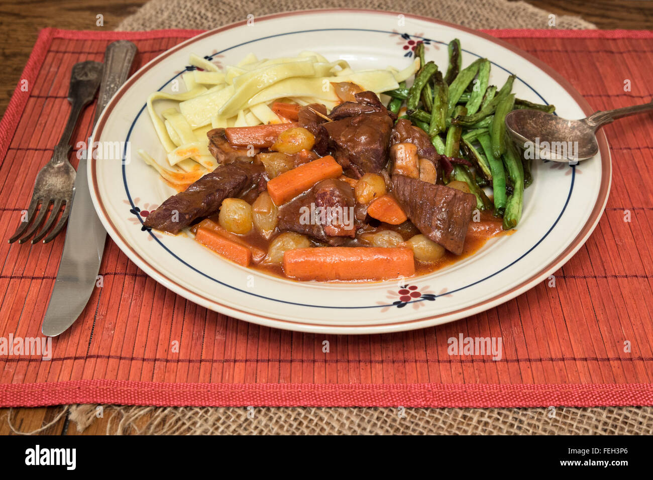 plate of heart beer bourguignon with noodles and beans Stock Photo