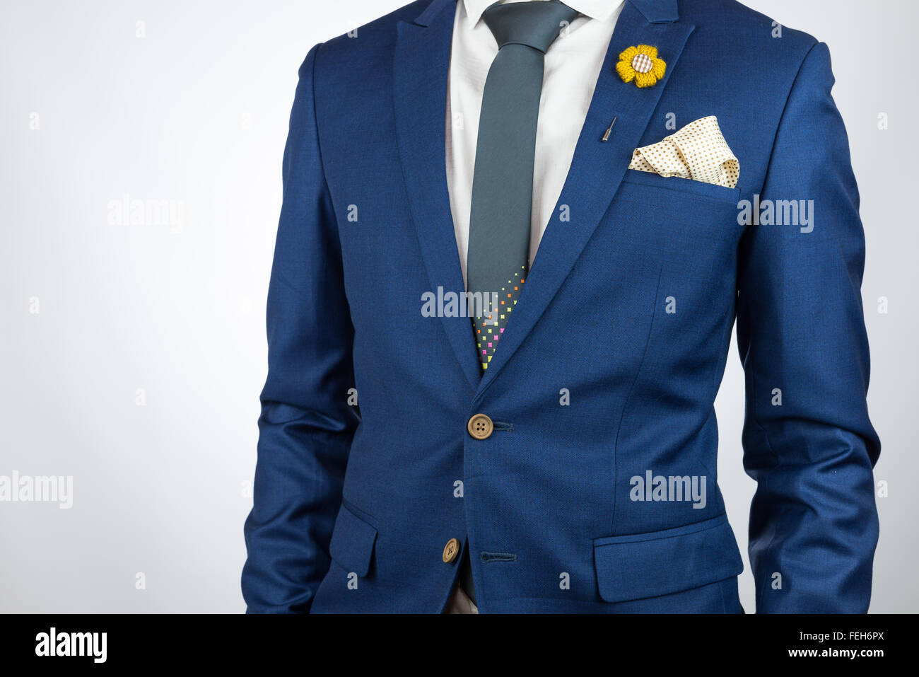 Man in blue suit with grey necktie, flower brooch, and dot pattern pocket  square, white background Stock Photo - Alamy