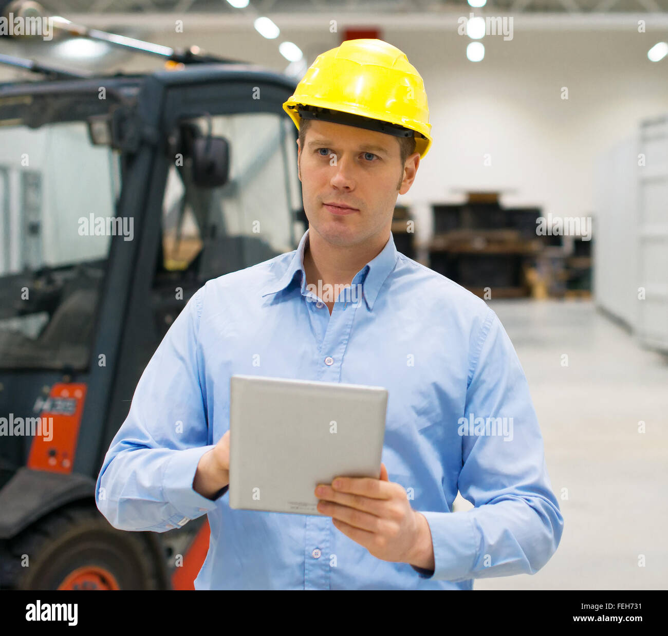Warehouseman in hard hat with tablet pc at warehouse. Stock Photo