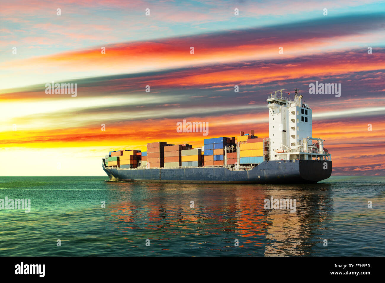 Sailing container ship at sunset on sea. Stock Photo