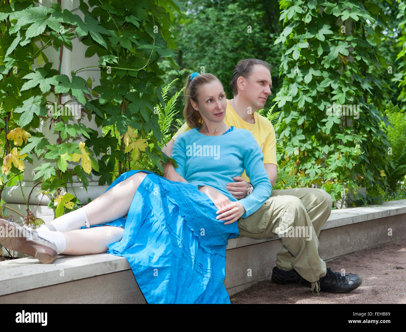 Happy man and the woman sit on a bench in park in the summer Stock ...