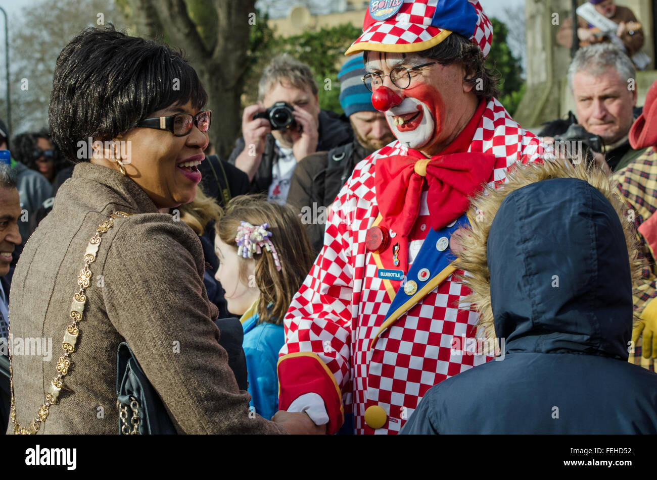 Hackney, London, UK. 7th February, 2016. Councillor Sade Etti, Deputy Speaker of Hackney Council, is welcomed to the Annual Clown Service by Bluebottle, also known as Tony Eldridge of Clowns International.  All Saints Church, Haggerston, where clowns are holding a memorial to Joseph Grimaldi, known as the King of Clowns. Credit:  Amanda Lewis/Alamy Live News Stock Photo